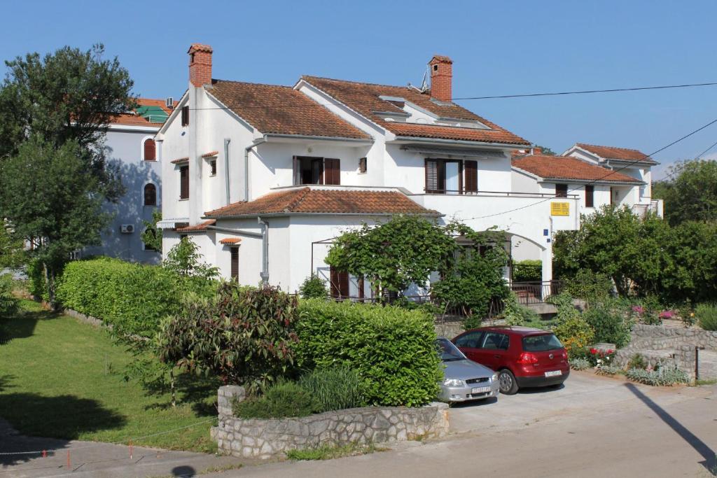 a white house with cars parked in front of it at Apartments with a parking space Vantacici, Krk - 5386 in Malinska