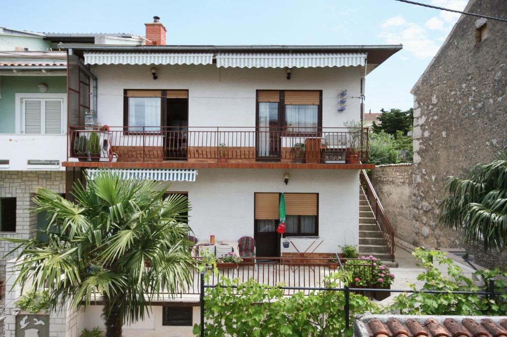 a white house with a balcony and palm trees at Apartments with WiFi Selce, Crikvenica - 5498 in Selce