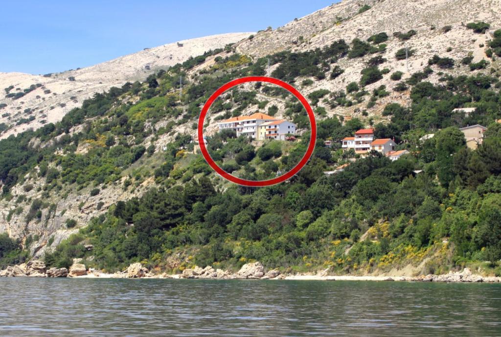 a house on a hill next to a body of water at Apartments and rooms with parking space Stara Baska, Krk - 5447 in Stara Baška