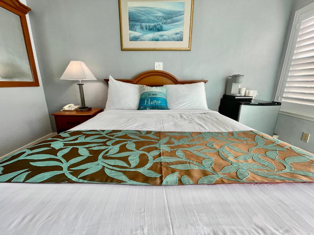 a bed in a hotel room with a blanket on it at The Palomar Inn in Pismo Beach