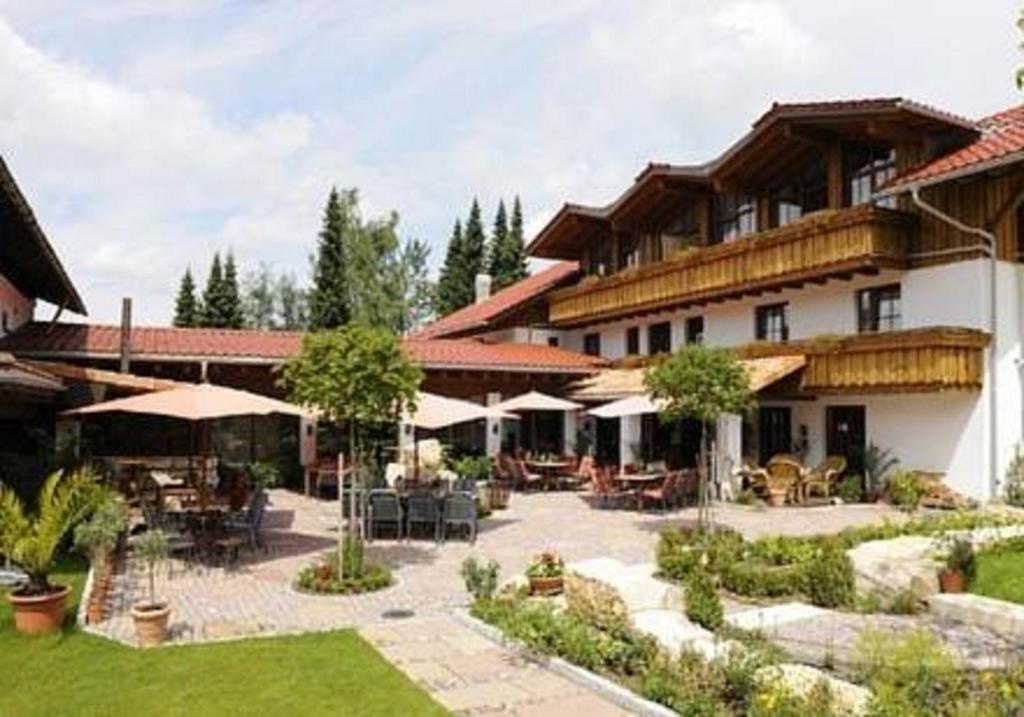 a large building with a courtyard with tables and umbrellas at Allgäuer Kräuteralm in Oberstaufen