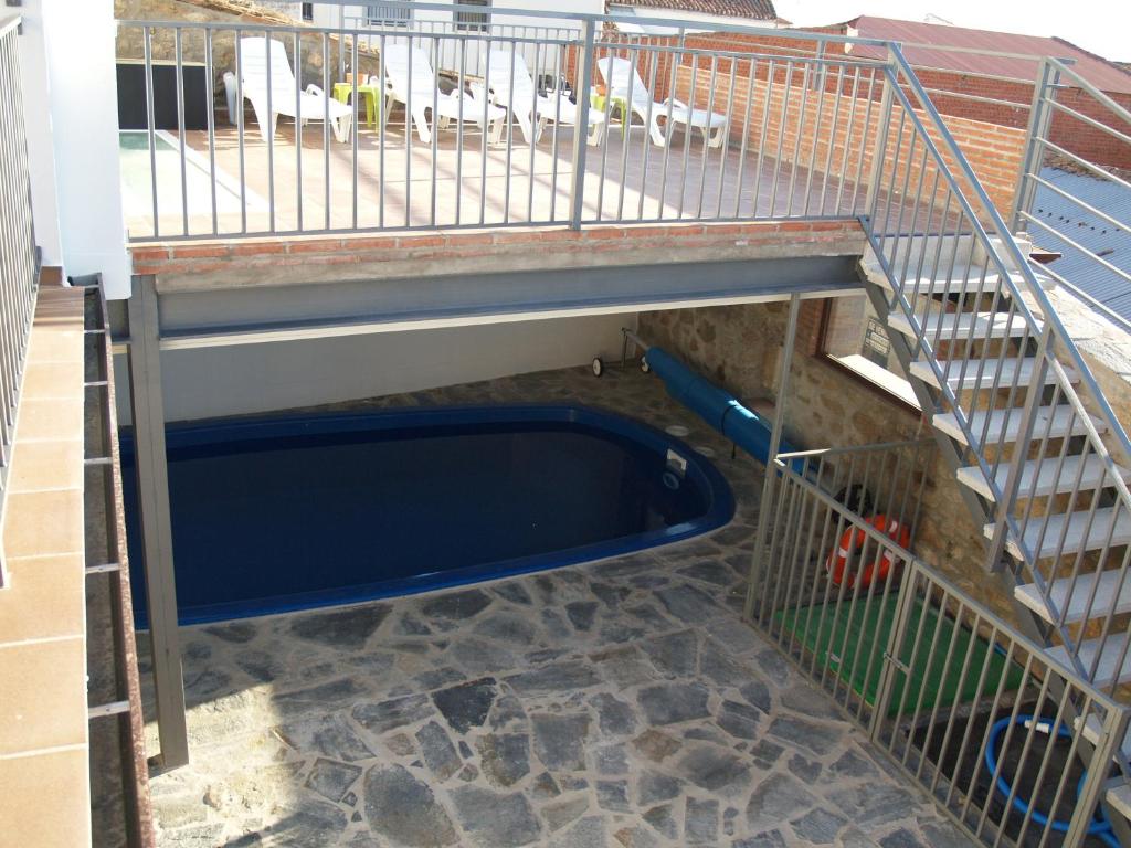 jaula de aves de corral con piscina azul bajo una escalera en Solaz del Ambroz, en Jarilla