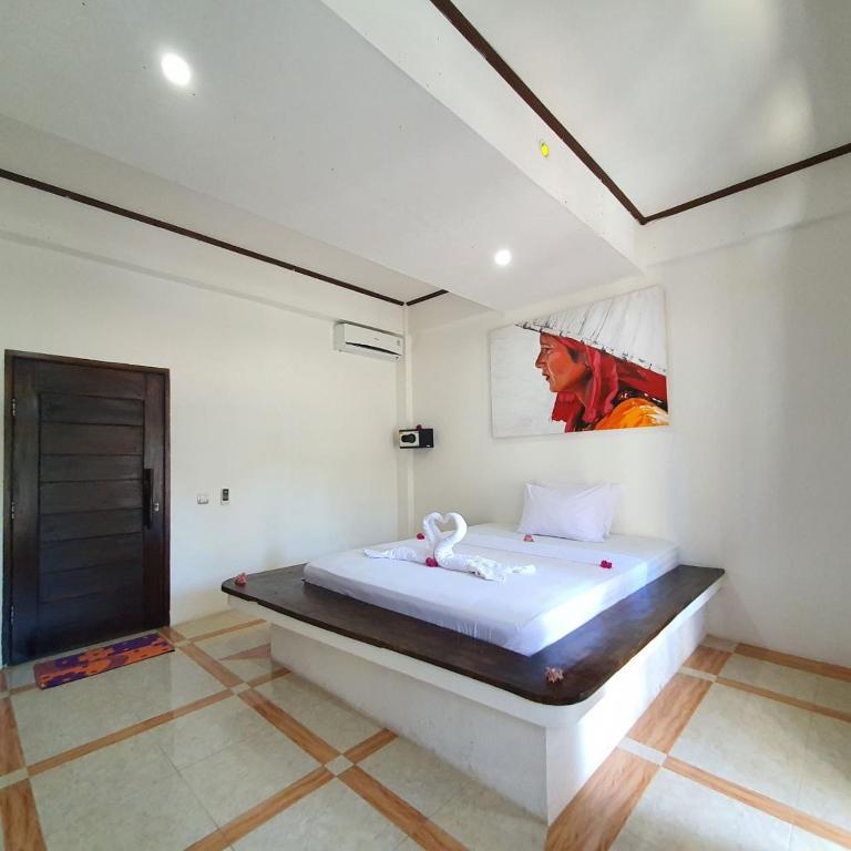 1 dormitorio con 1 cama y una pintura en la pared en Putra Boyan Cottages, en Gili Trawangan
