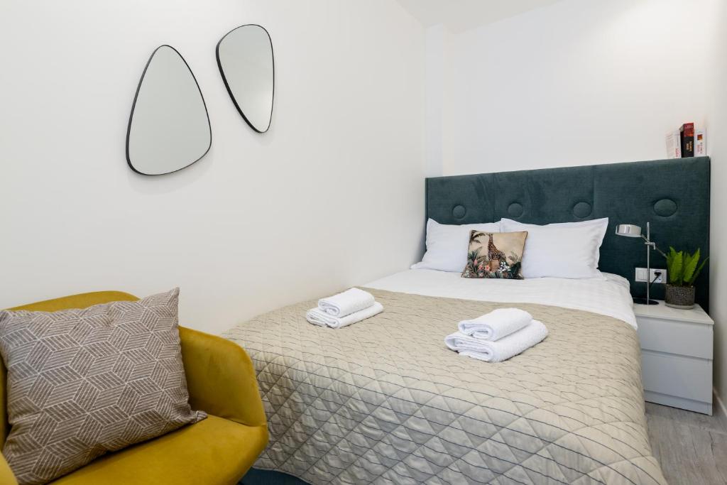 a bedroom with a bed and a yellow chair at Apartamenty Prestige Centrum in Bielsko-Biała