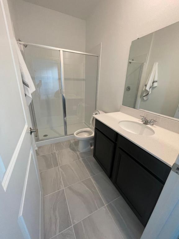 uma casa de banho com um chuveiro, um lavatório e um WC. em Cozy suites 4 less em Haines City