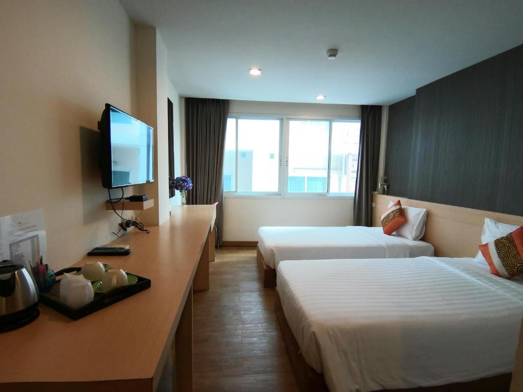 a hotel room with two beds and a flat screen tv at S3 Residence Park in Bangkok