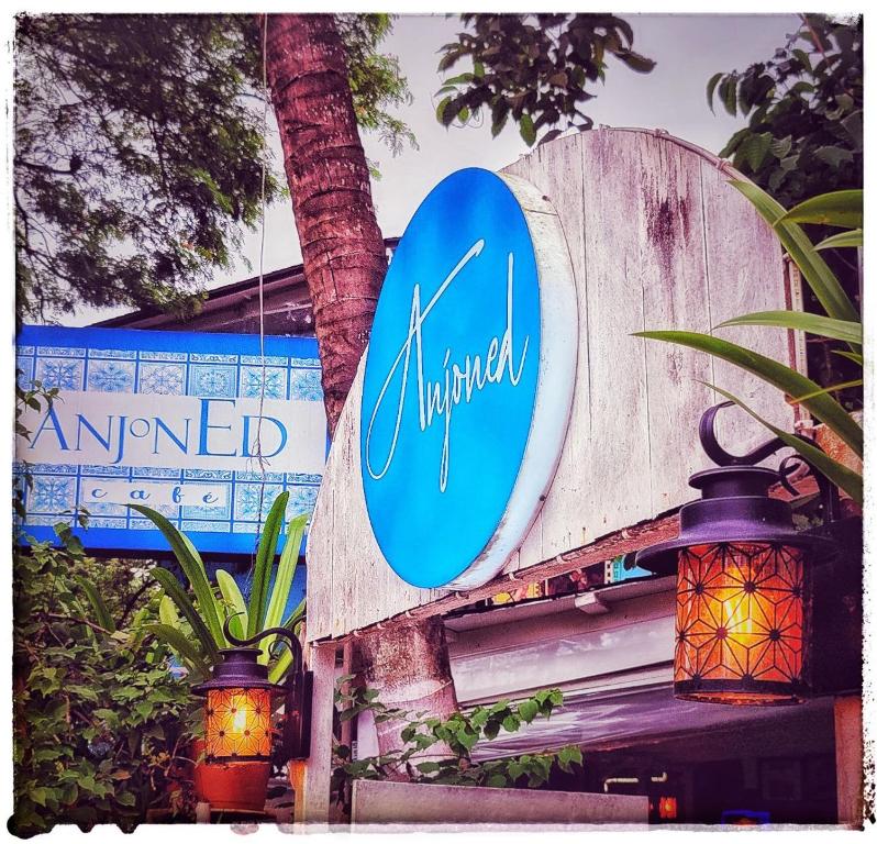 a sign on a wooden wall with two lights at Anjoned Hostel & Cafe in Anjuna