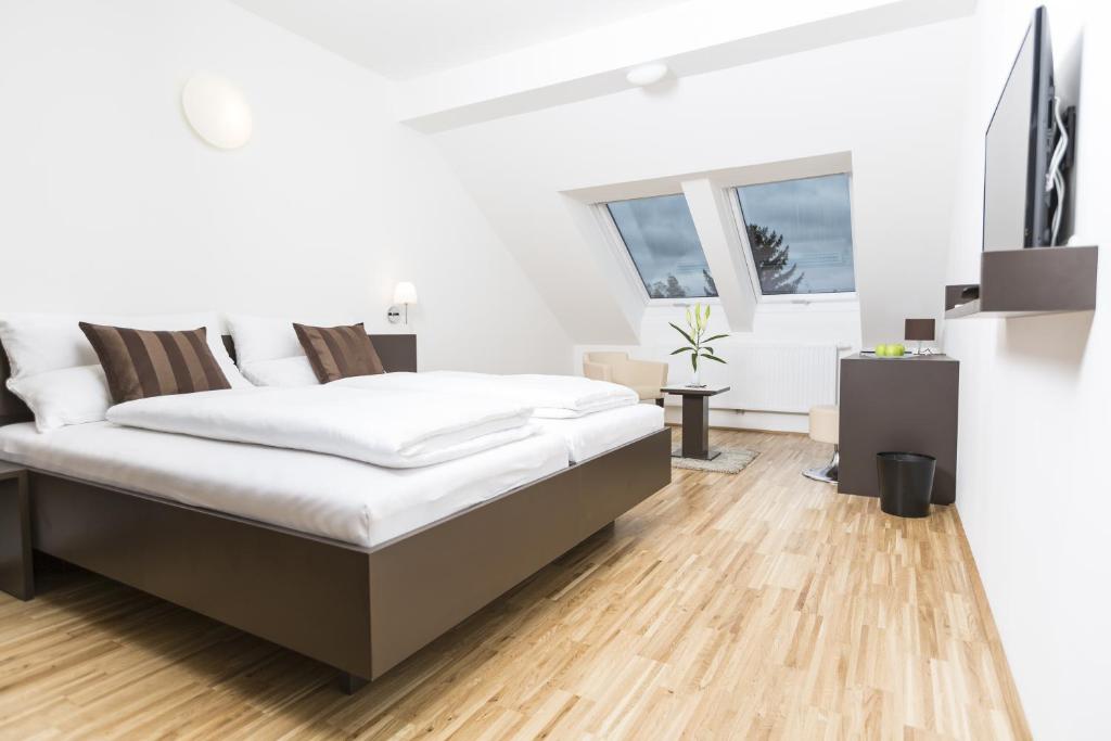 Gästezimmer by Jöchlinger في غيراسدورف بي فيين: غرفة نوم بيضاء مع سرير وأرضية خشبية