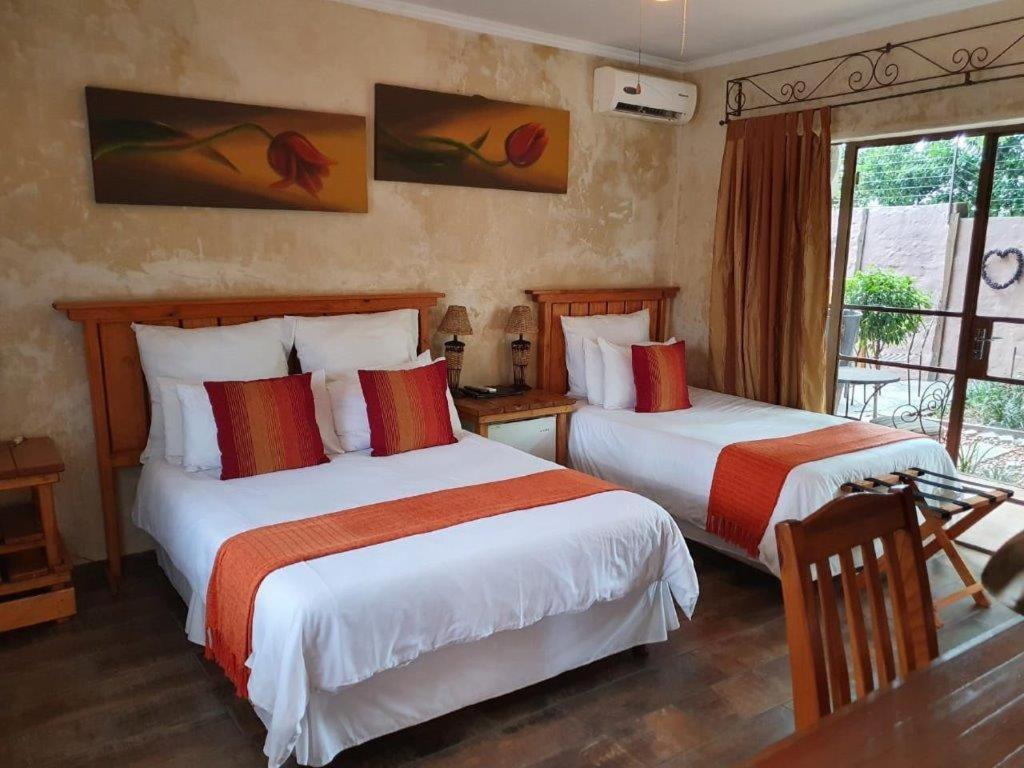 1 dormitorio con 2 camas con sábanas rojas y blancas en Claires of Centurion, en Centurion