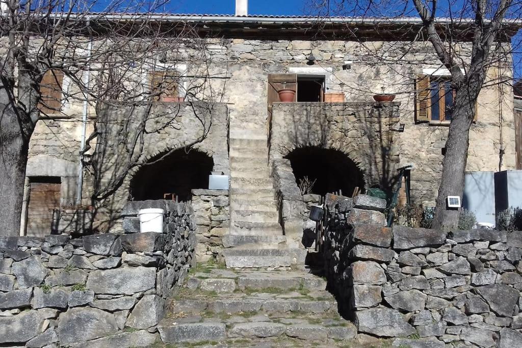 - un bâtiment en pierre avec des escaliers et un mur en pierre dans l'établissement Maison de caractère au coeur de la corse rurale, à Calacuccia