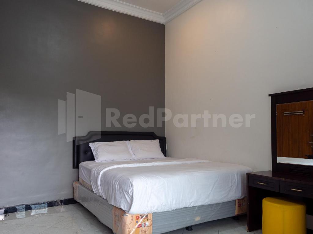 um quarto com uma cama com lençóis brancos e uma cómoda em Tjahaja Baroe Syariah Mitra RedDoorz At Dukuh Kupang em Surabaya