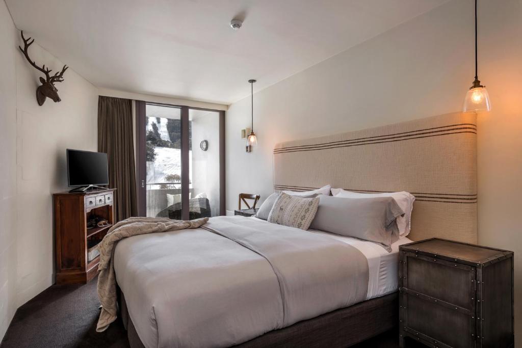 sypialnia z dużym białym łóżkiem i oknem w obiekcie Silver Run Thredbo w mieście Thredbo