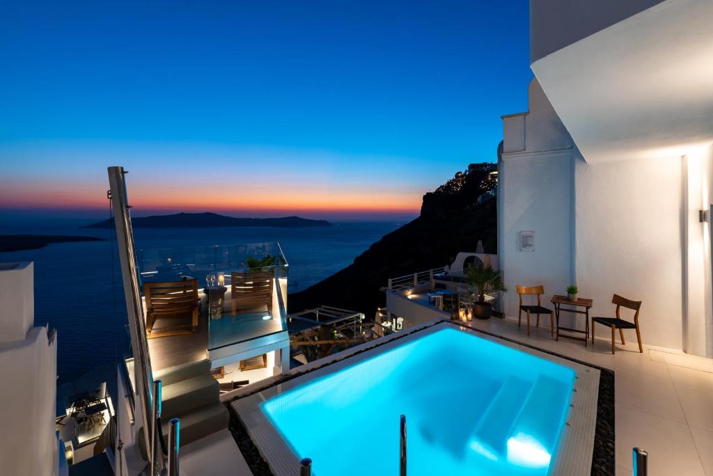 a villa with a swimming pool at night at Daydream Luxury Suites in Fira