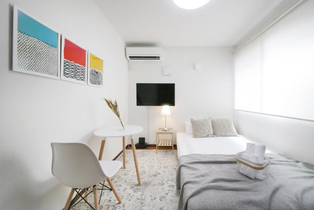 Habitación blanca con cama, mesa y TV. en アリア曳舟, en Tokio