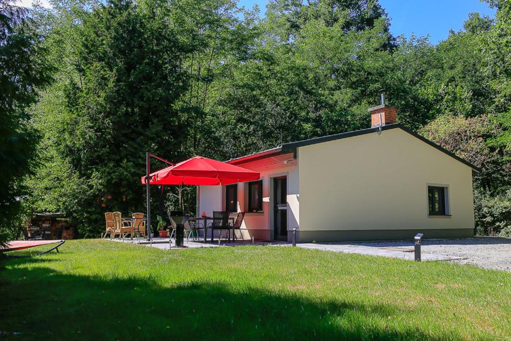 uma pequena casa com um guarda-chuva vermelho num quintal em Ferienhaus Crosta Brava em Großdubrau