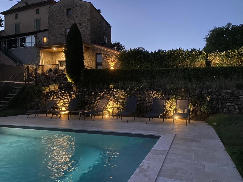 Villa con piscina frente a un edificio en Maison de village avec terrain et piscine dans le Parc Régional du Haut Languedoc, en Le Pradal