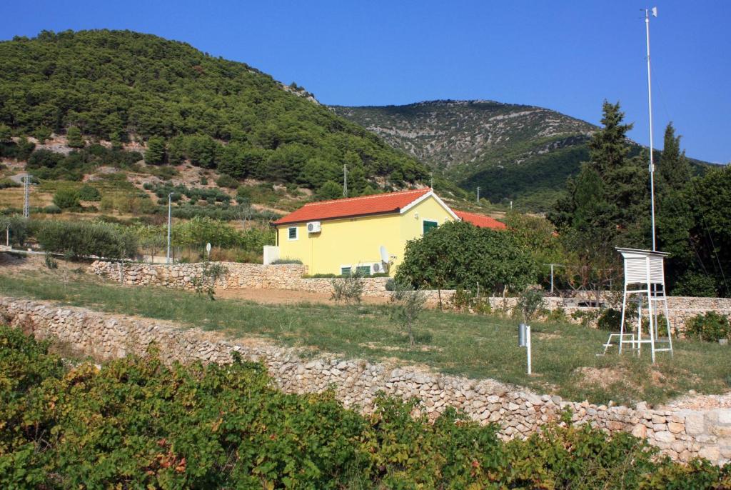 a yellow house in a field next to a mountain at Apartments with a parking space Bol, Brac - 5642 in Bol
