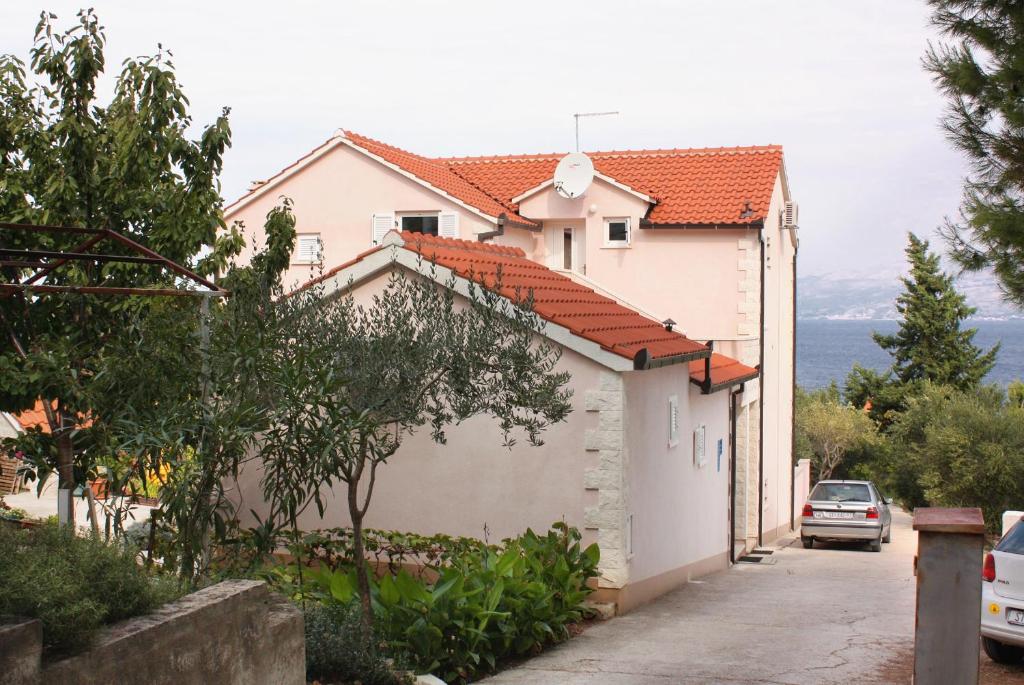 a house with a car parked in front of it at Apartments by the sea Splitska, Brac - 5664 in Splitska