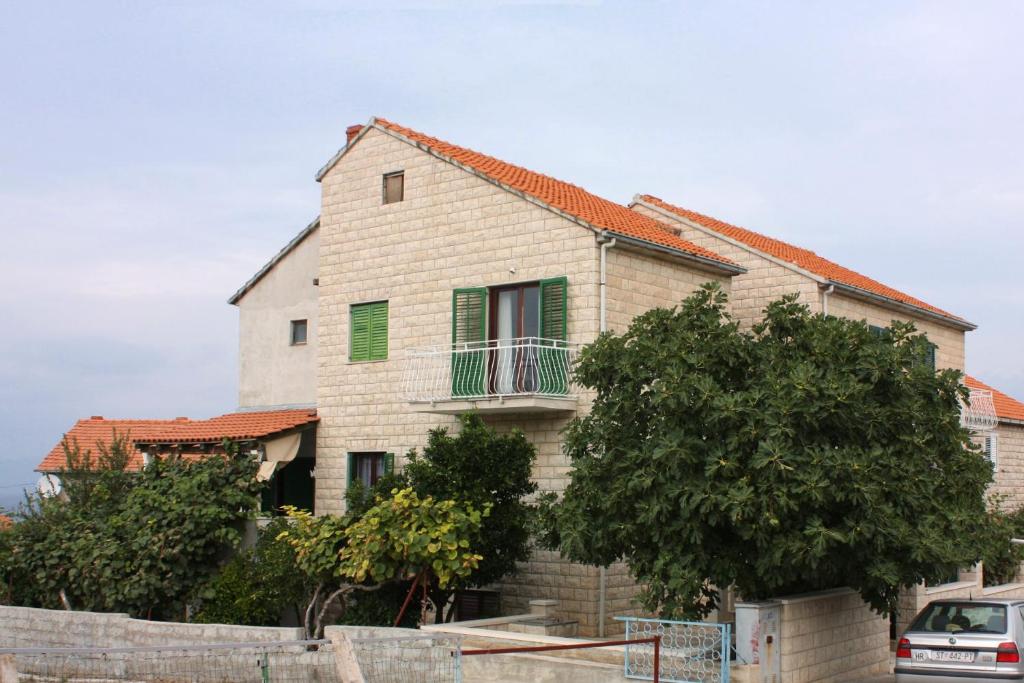 Casa blanca con ventanas verdes y valla en Apartments with WiFi Supetar, Brac - 5667, en Supetar