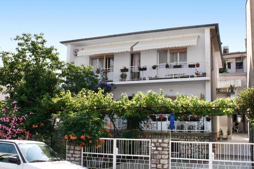 a white apartment building with a white fence and flowers at Apartments by the sea Selce, Crikvenica - 5550 in Selce