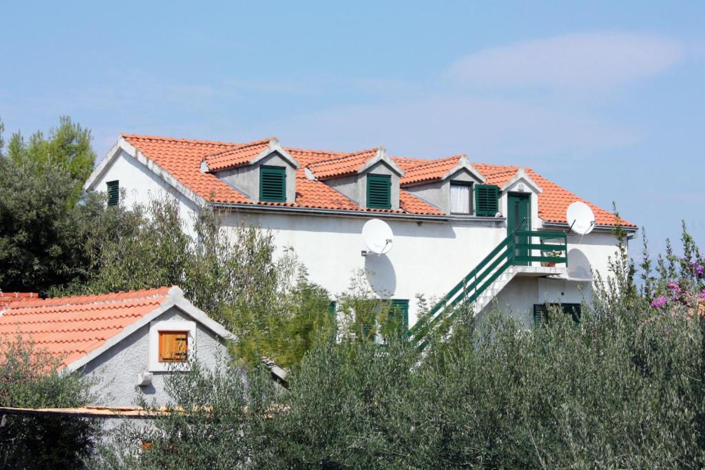 biały dom z czerwonymi dachami i drzewami w obiekcie Apartments by the sea Mirca, Brac - 5655 w mieście Mirce