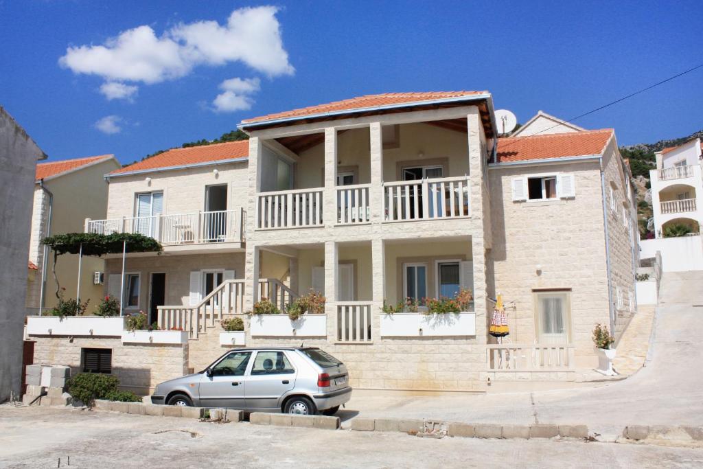 a house with a car parked in front of it at Apartments with a parking space Bol, Brac - 5641 in Bol