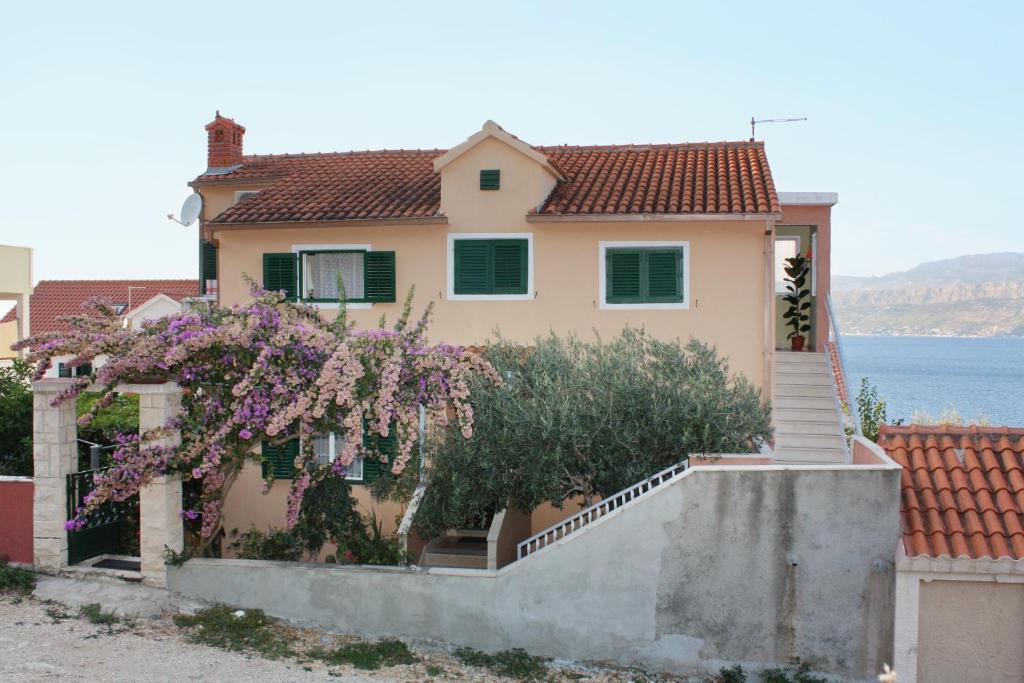 a house with a flowering tree in front of it at Apartments with a parking space Postira, Brac - 5618 in Postira