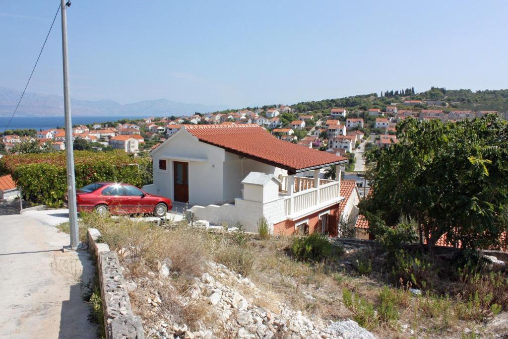 a house on a hill with a red car in front at Apartments with a parking space Sutivan, Brac - 5654 in Sutivan