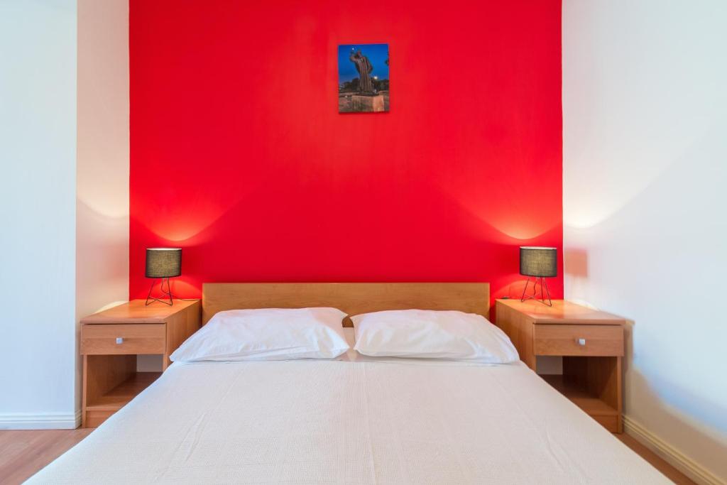 a bedroom with a red wall and a bed with two lamps at Studio Nin 5666b in Nin