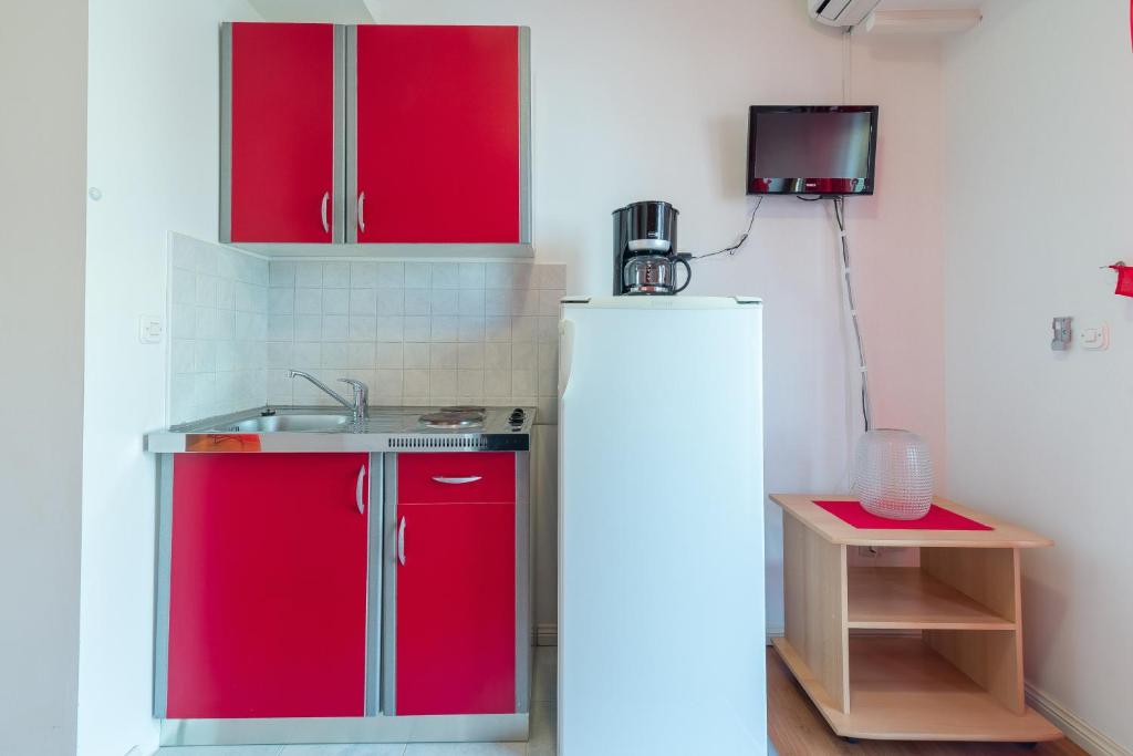 a kitchen with red cabinets and a sink and a refrigerator at Studio Nin 5666b in Nin