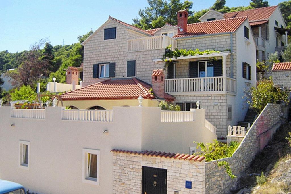 una gran casa blanca en la parte superior de una pared en Family friendly house with a swimming pool Postira, Brac - 5661, en Postira