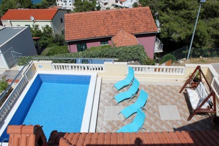 a swimming pool with two blue stairs next to a house at Family friendly house with a swimming pool Postira, Brac - 5661 in Postira