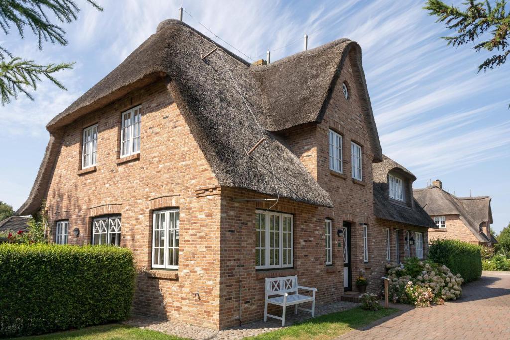 an old brick house with a thatched roof at Landhaus Timmi in Midlum