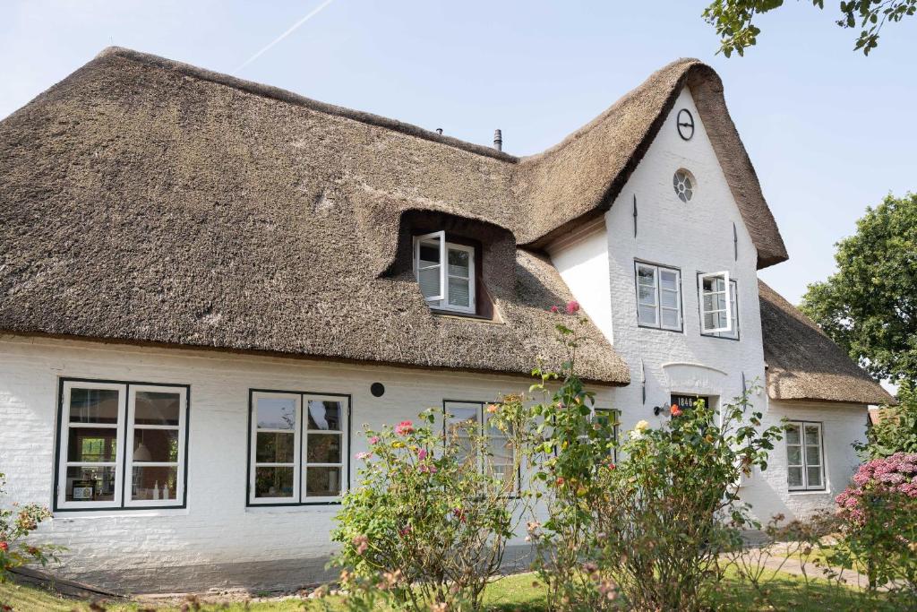 a white house with a thatched roof at Altes Schulmeisterhaus Wohnung 1 in Oevenum