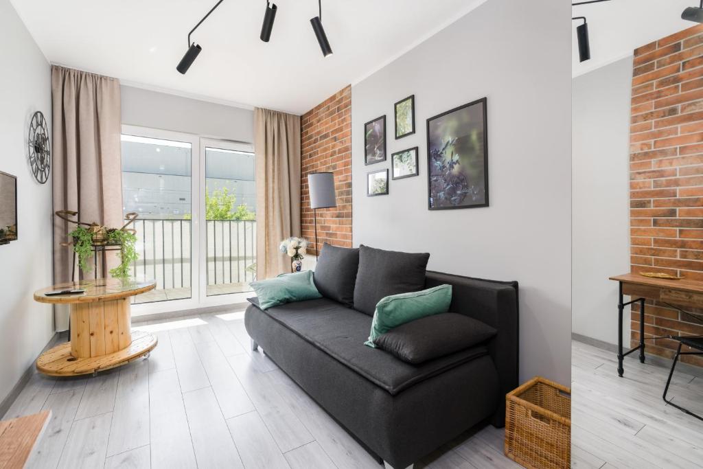 a living room with a black couch and a brick wall at Family Apartment 62m - Sowia with GARAGE & BALCONY by Renters in Poznań