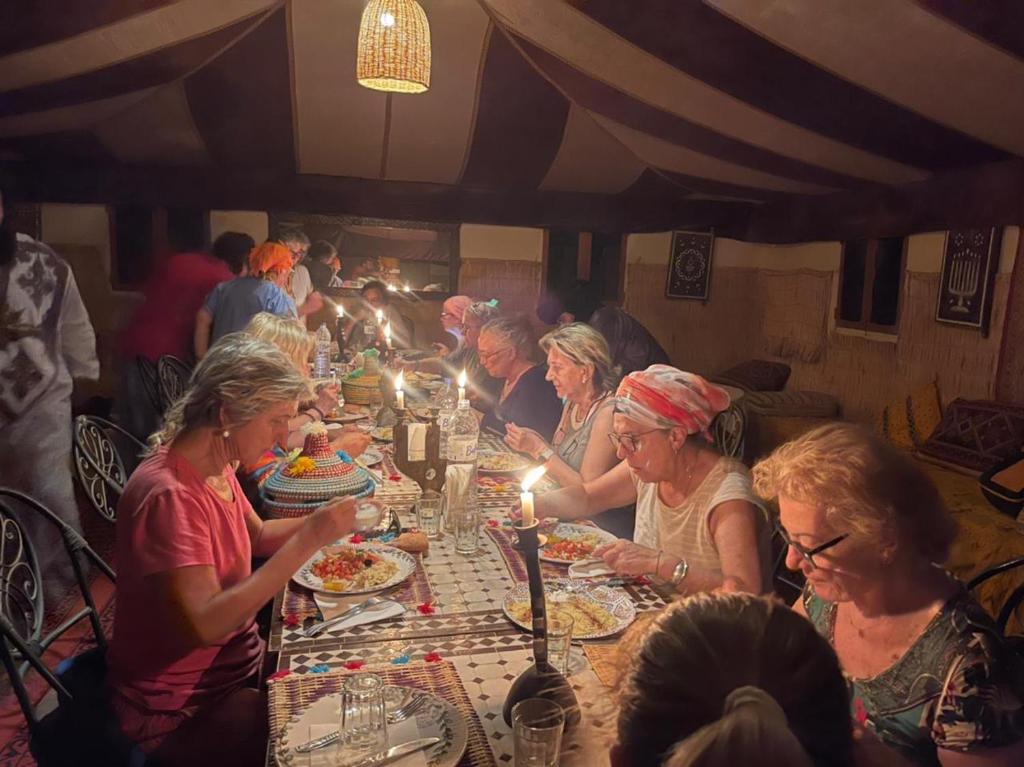 Eine Gruppe von Menschen, die an einem Tisch sitzen und Essen essen. in der Unterkunft berber sahara in Zagora