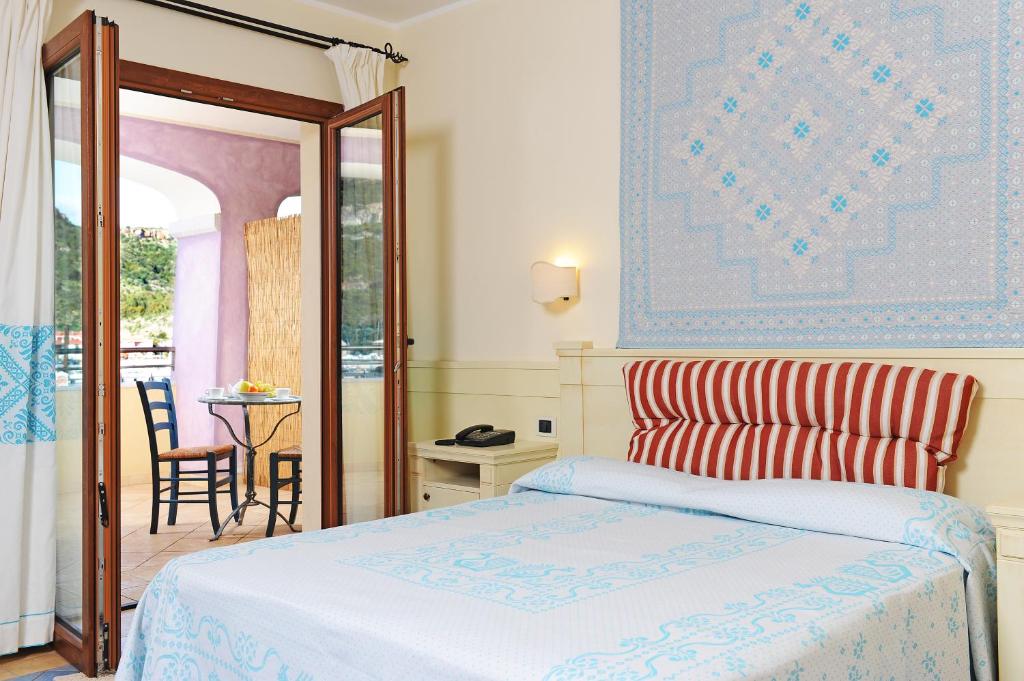 een slaapkamer met een bed en een tafel met een stoel bij Hotel Baja Romantica in Bosa