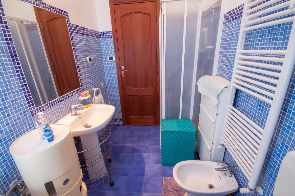 a blue tiled bathroom with a toilet and a sink at Limoni Sul Mare in Torre Faro