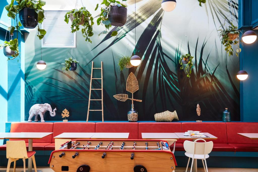 a restaurant with a red couch and a mural of plants at ibis Styles Toulon Centre Port in Toulon