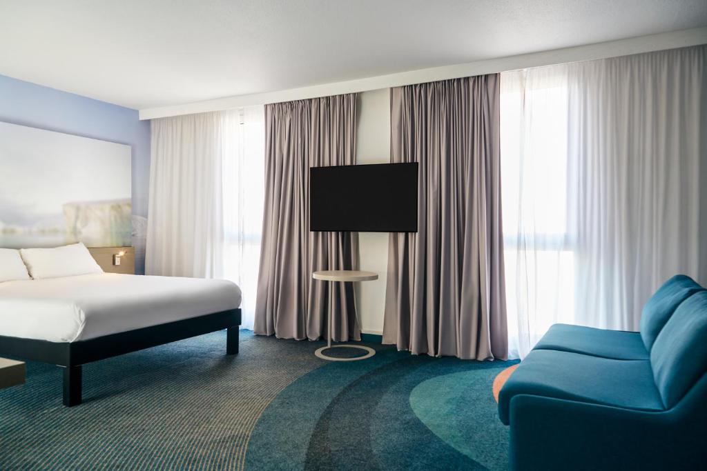 a hotel room with a bed and a blue couch at ibis Styles Toulon Centre Port in Toulon