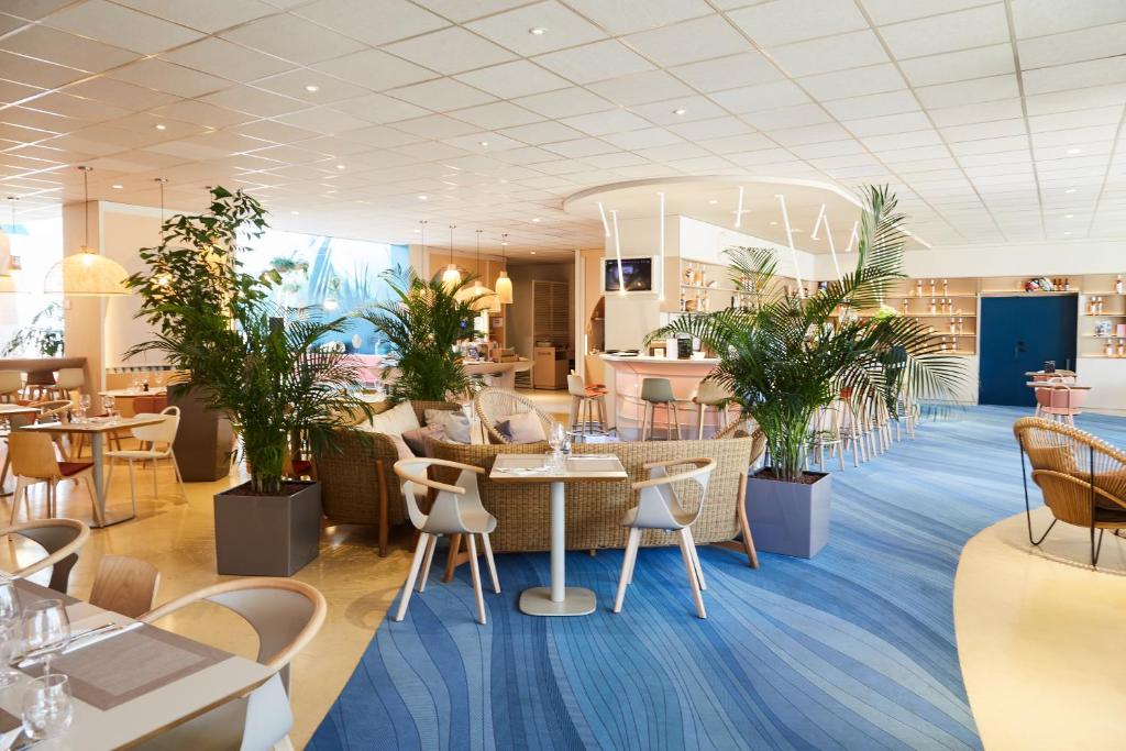 a restaurant with tables and chairs and plants at ibis Styles Toulon Centre Port in Toulon