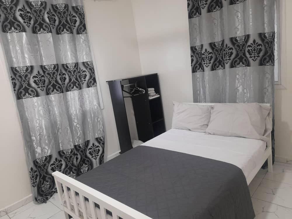 een slaapkamer met een bed met zwart-witte gordijnen bij Tapis Guest House in Brikama