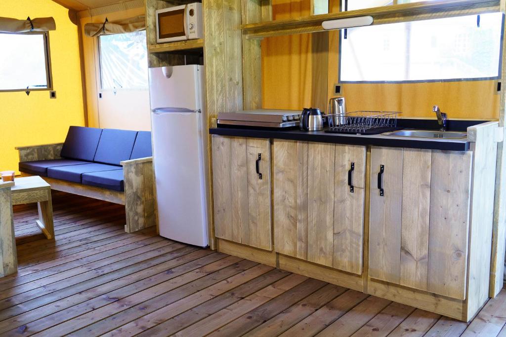 a kitchen with a refrigerator and a couch in a room at LE LODGE DU DOMAINE in Saint-Hilaire-en-Morvan