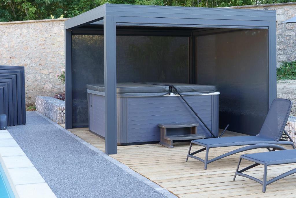 a gazebo with a hot tub and a chair at LE LODGE DU DOMAINE in Saint-Hilaire-en-Morvan