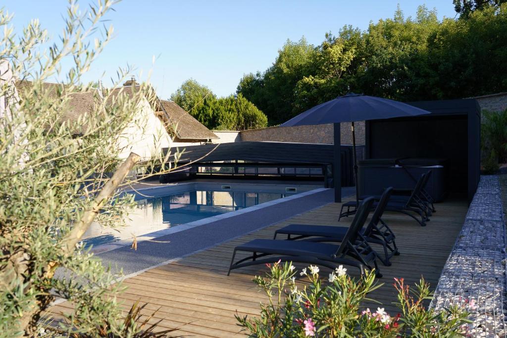 a deck with chairs and an umbrella next to a pool at LE LODGE DU DOMAINE in Saint-Hilaire-en-Morvan