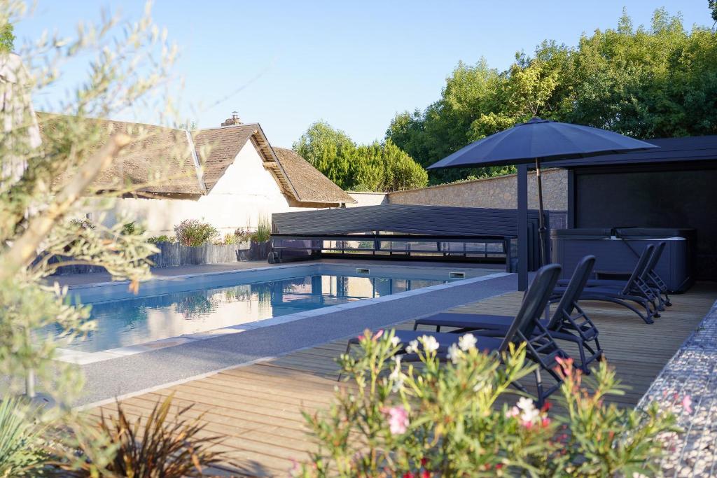 a swimming pool with two chairs and an umbrella at LE LODGE DU DOMAINE in Saint-Hilaire-en-Morvan
