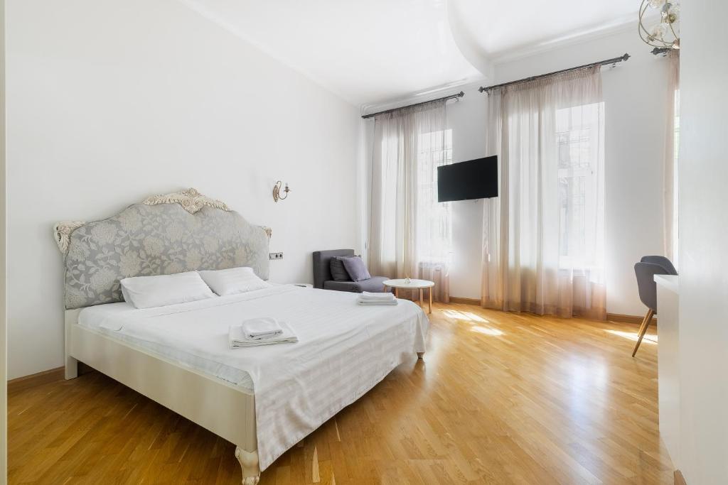 a white bedroom with a bed and a chair at KayKay Apartments in Odesa