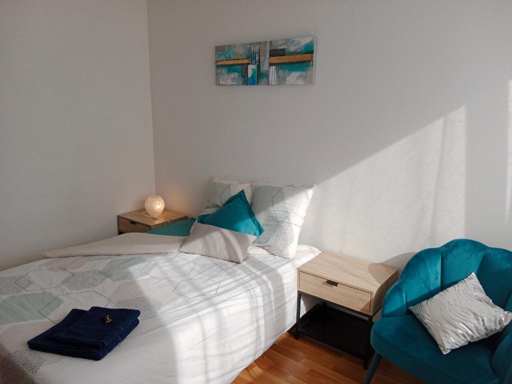 a bedroom with a bed and a blue chair at Chambre #2 dans appartement partagé - Proche des Vosges in Thann