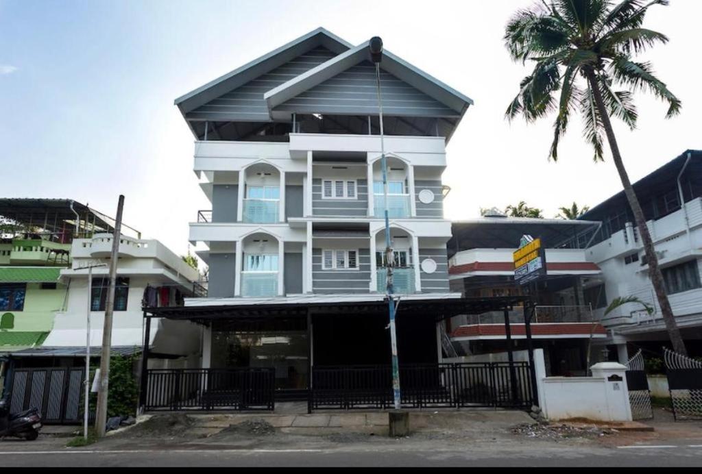 een hoog wit gebouw met een palmboom ervoor bij Salamath Homestay in Cochin