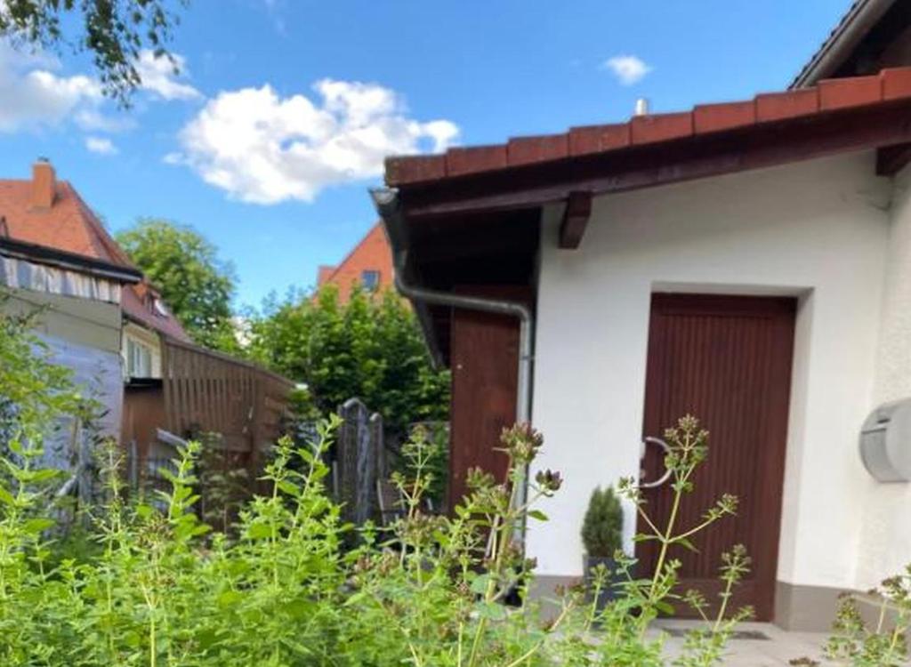 a white building with a brown door in a yard at Ferienwohnung an der Brigach in Donaueschingen